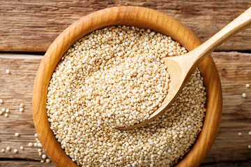 Traditional raw quinoa close up in a wooden bowl on the table. top view horizontal background