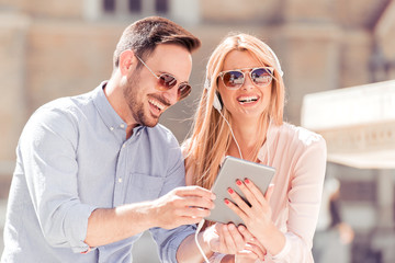 Couple in city using digital tablet and listening music.