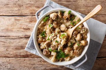 Tasty quinoa with mushrooms, parsley and onion close-up on the table. Horizontal top view