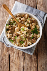 Tasty quinoa with mushrooms, parsley and onion close-up on the table. Vertical top view