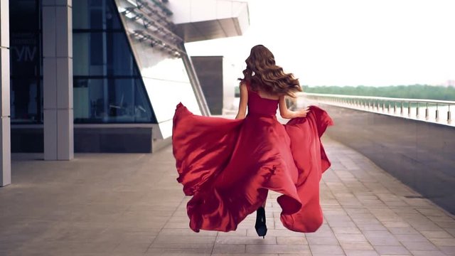 Beautiful woman run in red fluttering dress. Slow motion.