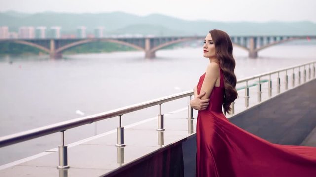 Beautiful woman in red dress outdoor. City background.