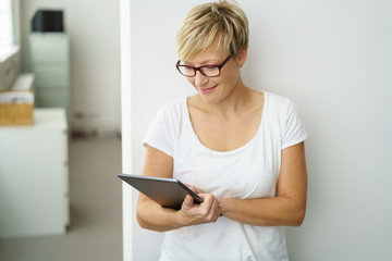 lächelnde mitarbeiterin im büro schaut auf ihr tablet