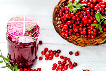 Cranberry jam in a jar on white wooden table