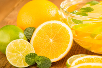 Fototapeta na wymiar Glass bowl with detox water with slices of orange and lime. Close-up.