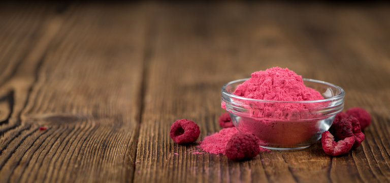Portion of Raspberry powder on wooden background, selective focus