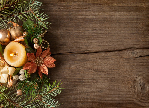 Fir branch with Christmas decorations  and candle on the background of old wooden plank.