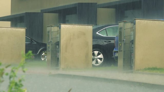 Heavy rain on the street with parked cars and houses 