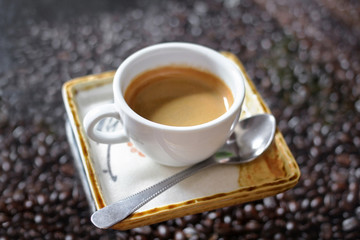 Cup of Coffee with crema on coffee beans blur background.