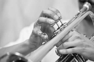 Hands of a musician playing on a trumpet closeup in black and white tones