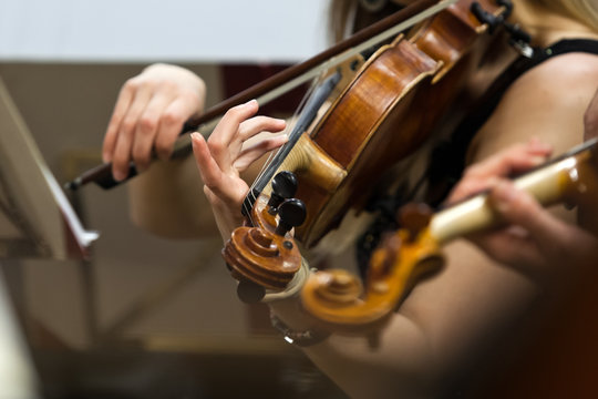  Hands of a girl playing the violin in the orchestra 