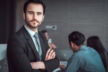 business man standing with his staff in background at meeting room   