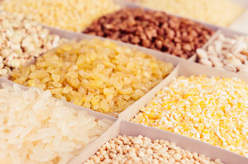 Assortment different groats as background, closeup. Wheat pearl, bulgur, millet, rice, couscous, semolina, corn grits, buckwheat, quinoa.