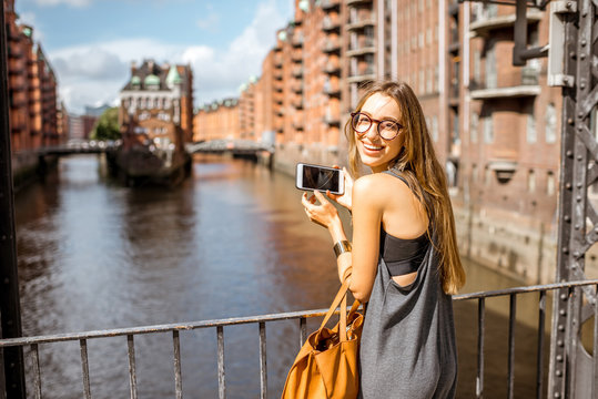 Young woman tourist photographing beautiful view on the Speicherstadt, historic warehouse district in Hamburg, Germany