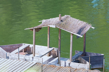 Boat bridge with wooden boat and thatched roof.