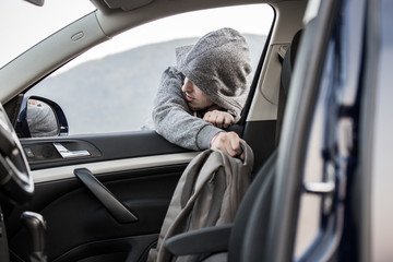A thief, a criminal, thrust his hand out of the car window and takes a backpack, steals private...