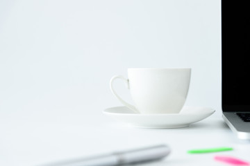 Coffee Cup and computer desktop on white office desk table with a silver pen and note for working in the morning with closeup view and copy space conecpt.