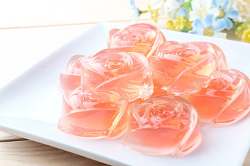 Jelly in rose shape in plate on wooden background
