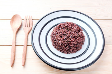 Brown Rice with wooden spoon on wooden background