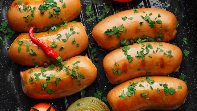 Fried sausages with herbs and vegetables in grill pan