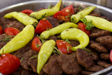 Beef cutlets baked on the grill with vegetables and sweet peppers and tomatoes with greens