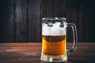 Mug of beer on the wooden background