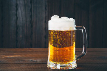 Mug of beer on the wooden background