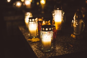 Burning candles at a cemetery during All Saints Day - obrazy, fototapety, plakaty