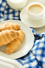 Traditional breakfast with fresh croissants, milk and espresso on white wooden salver . Selective focus