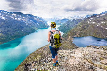 Obraz premium Young woman hiking on Besseggen. Happy girl enjoy beautiful lake and good weather in Norway.