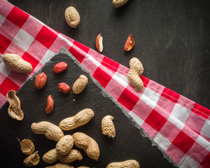 Fresh peanuts in peel and shell. Dark wooden background. Vegetarian food.