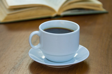 Cup of coffee and book on wooden table