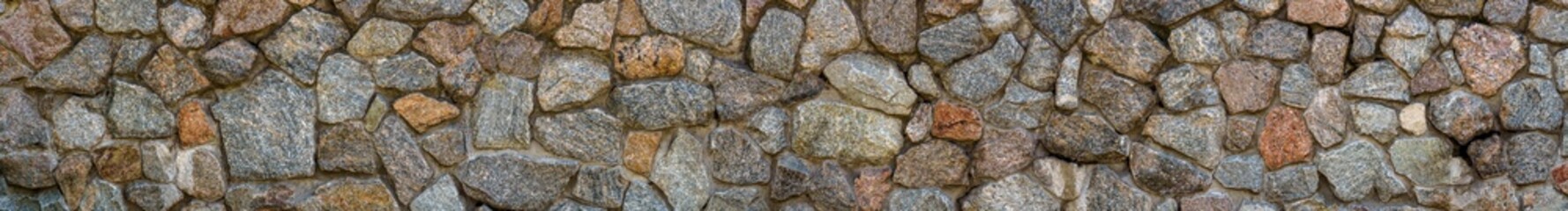 Textured stone walls built of large rough stones held together by dark lumps of gray cement limestone. Handcraft tile stone wall as background.