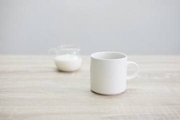 WHITE COFFEE CUP WITH MILK JAR
White coffee cup with transparent milk jar on the wood table. 
