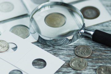 Different old coins and magnifying glass, Soft focus background