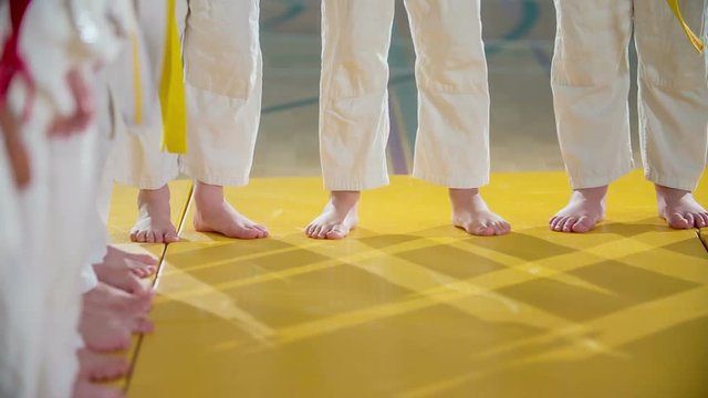 Boys are barefoot in a judo class. They are wearing white uniforms and are also having yellow and red belts on.