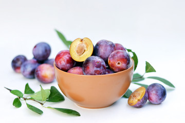 Ripe plums in a bowl and slices of plum.