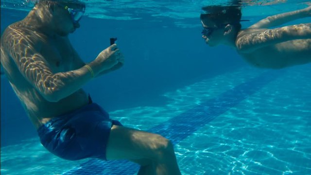 father taking pictures of son on an underwater smartphone
