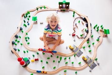 Child with toy train. Kids wooden railway.