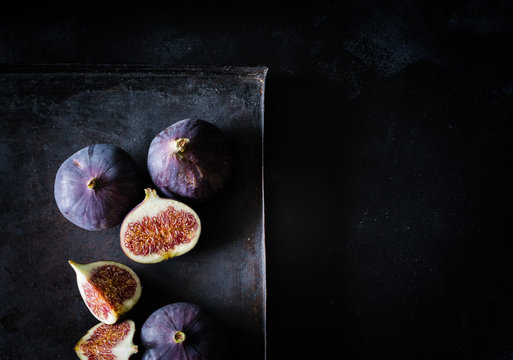 Feigen als ganze Frucht und im Anschnitt von oben auf schwarzem Untergrund bei Tageslicht fotografiert