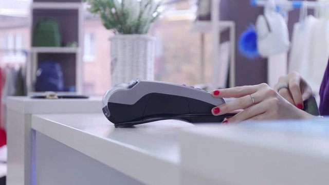 Shop assistant inserting a credit card into a pos and tearing off a receipt