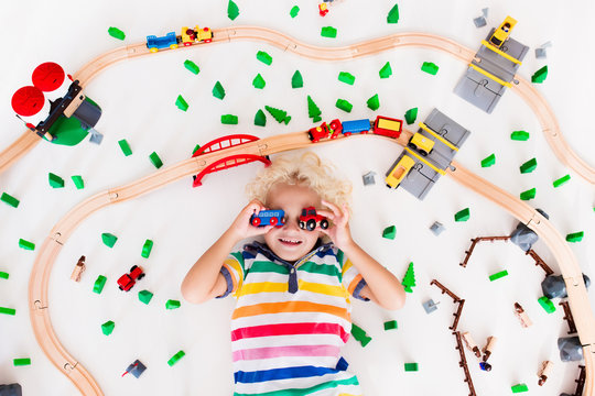 Child with toy train. Kids wooden railway.