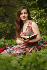 A young beautiful woman with a book  sitting on the grass 
