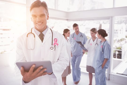 Composite image of smiling doctor holding digital tablet