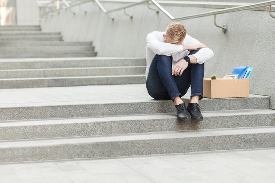 Unhappy red hair and bearded business man siting with cardboard, holing head and feeling sad and cry.