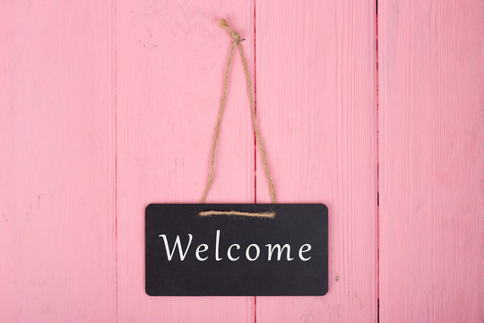 Blackboards with inscription "Welcome" on pink wooden background