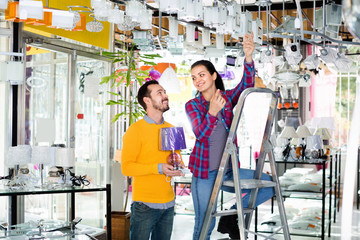 Smiling man and girl in lighter shop choosing stylish pendant lamp