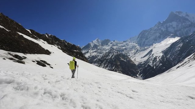 A girl with a backpack rises to the mountains in the snow. Nepal Himalayas