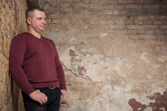 Portrait of adult man staying against the background of a peeling wall