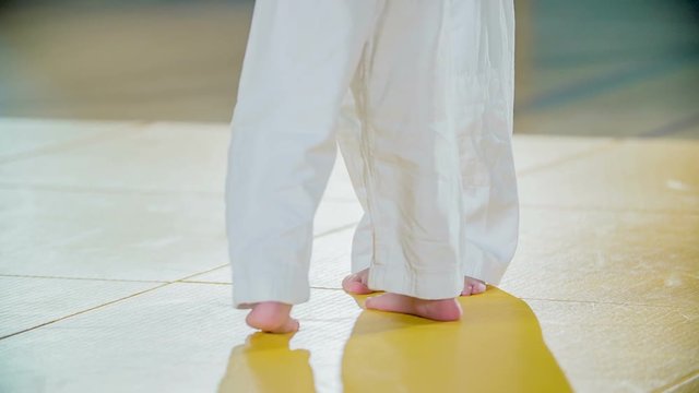 A young girl is practising one of the judo moves together with another girl. She is throwing her over a shoulder on the floor.